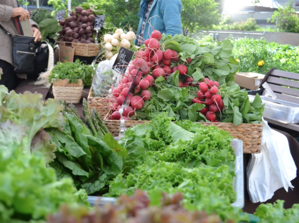 Photo d'étallages de légumes dans un marché extérieur.