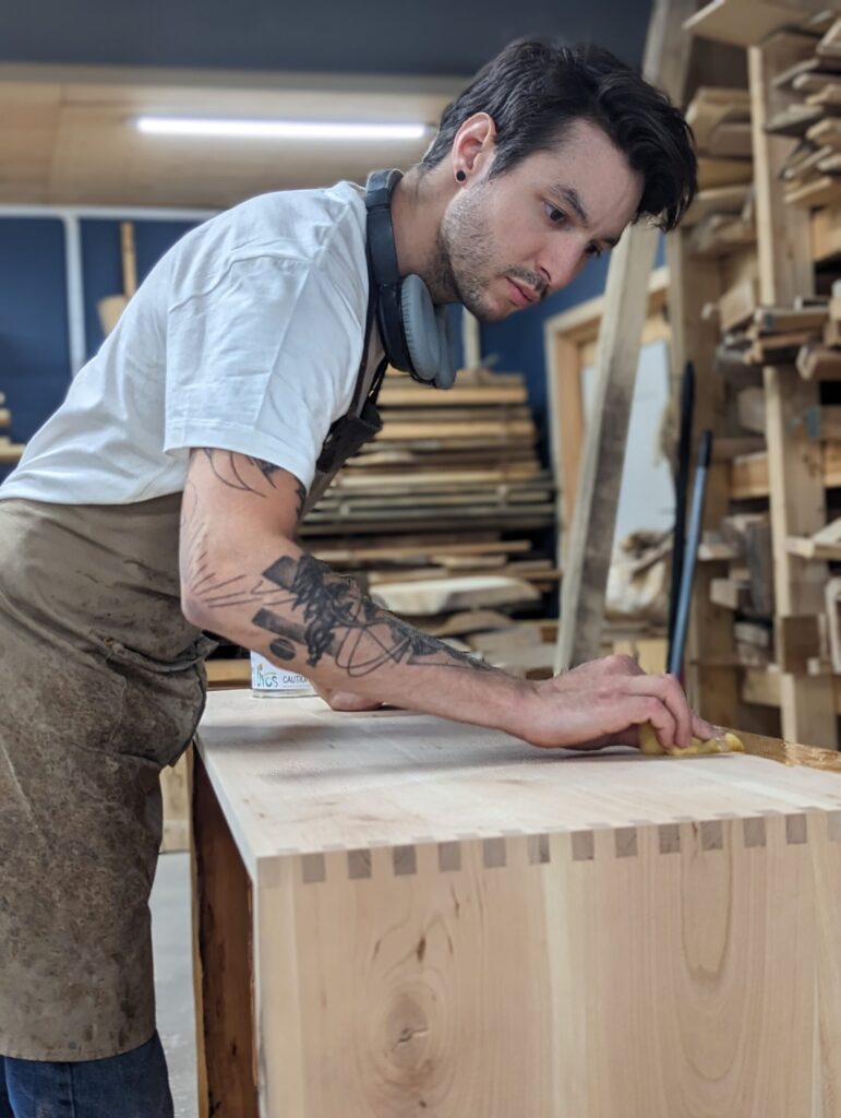 Danou Charette travaillant sur un meuble en bois.